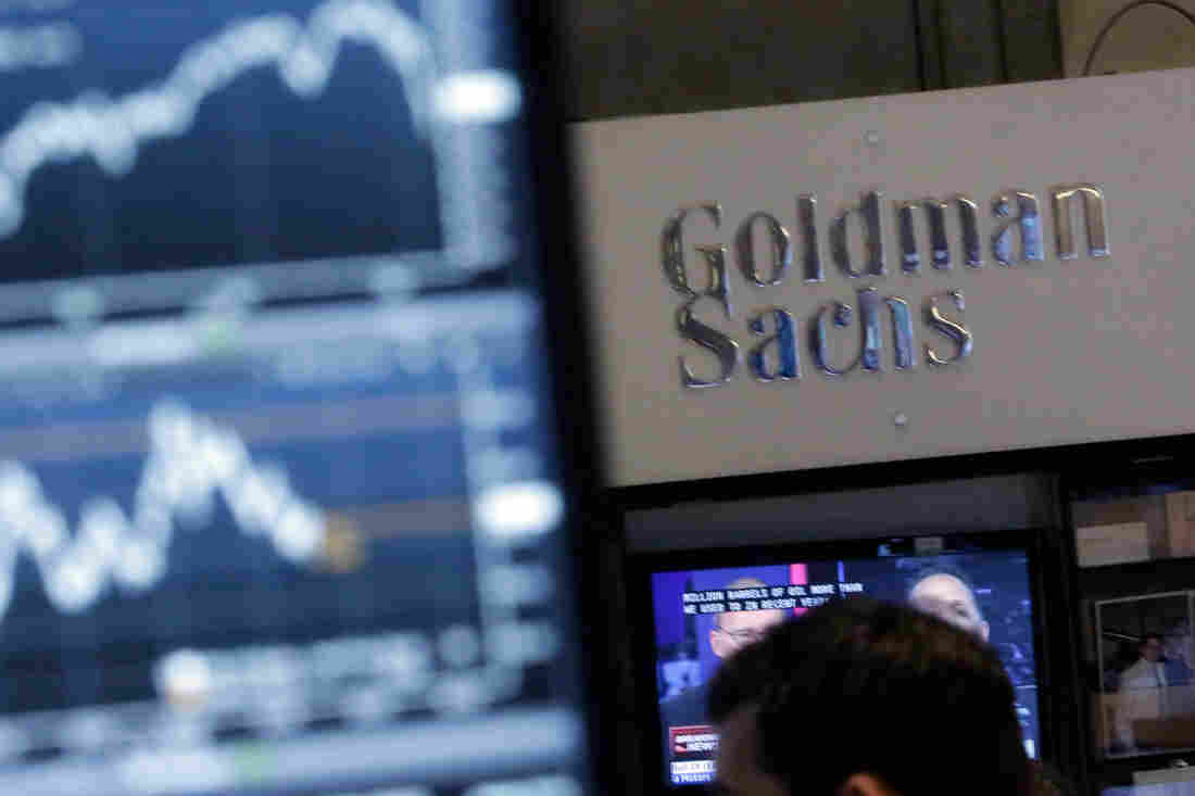 A screen at a trading post on the floor of the New York Stock Exchange is juxtaposed with the Goldman Sachs booth on Oct. 16, 2014.