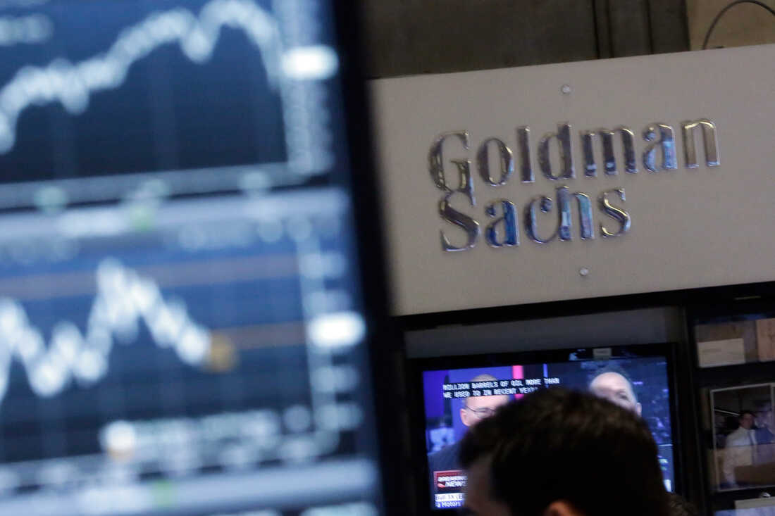 A screen at a trading post on the floor of the New York Stock Exchange is juxtaposed with the Goldman Sachs booth on Oct. 16, 2014.