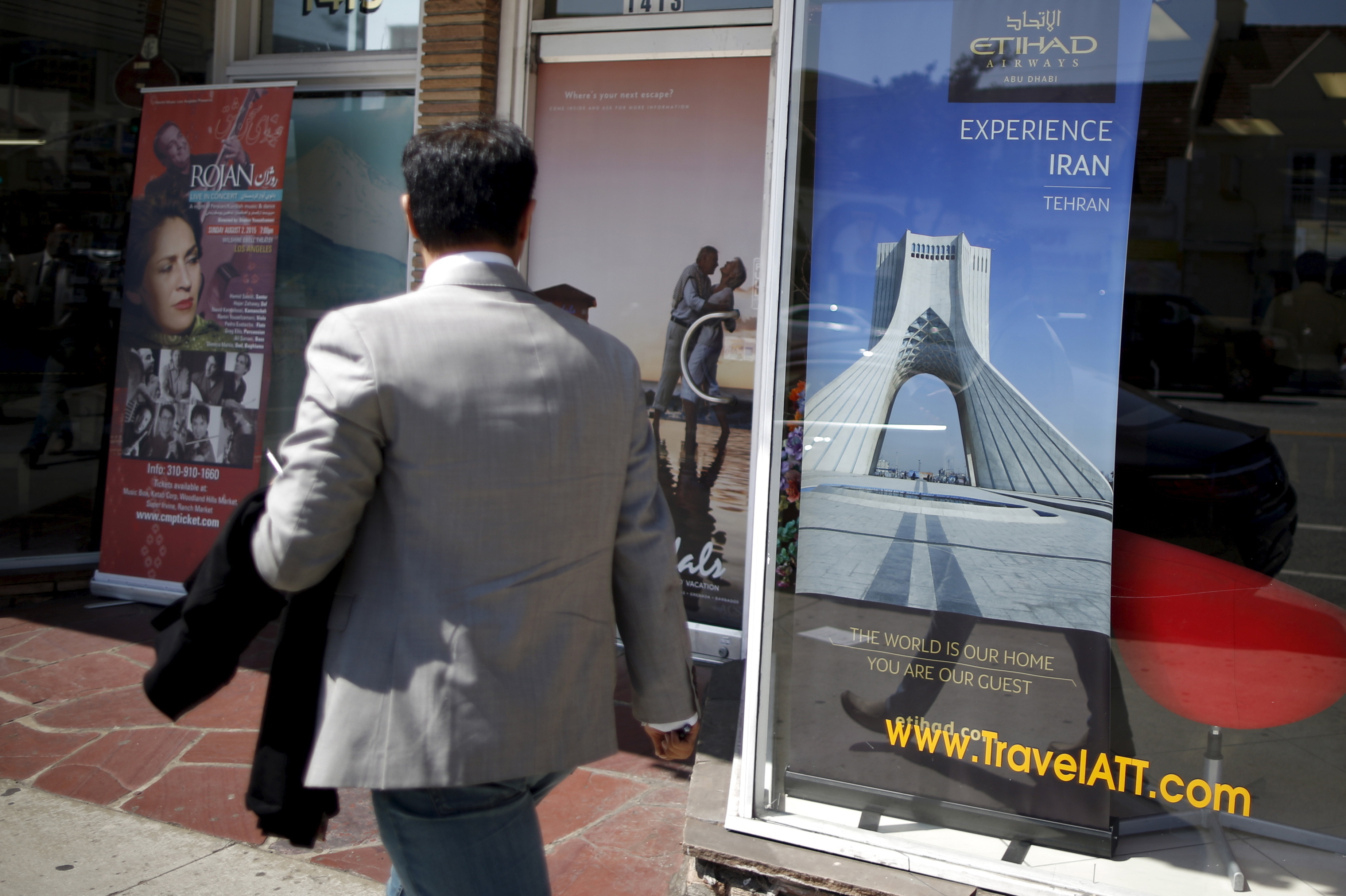 A man walks past a poster advertising travel to Tehran, Iran, in Los Angeles on July 14. A nuclear deal between Iran and six world powers lifts some sanctions against Iran, but most U.S. sanctions will remain in place.