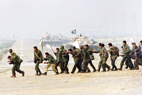 Iraqi soldiers cross a highway carrying white surrender flags on Feb. 25, 1991, in Kuwait City. The U.S.-led coalition overwhelmed the Iraqi forces and swiftly drove them out of Kuwait.