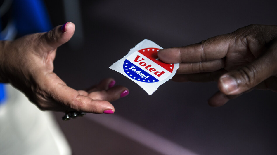 A poll worker hands out "I Voted Today" stickers in Washington, D.C., in 2012. Journalist Ari Berman says a 2013 Supreme Court ruling opened the door for new voting restrictions that disproportionately affect poor people, young people and people of color. (Brendan Smialowski/AFP/Getty Images)