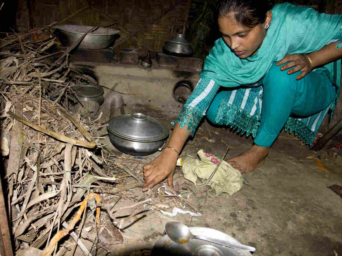 Minu gathers sticks to place under the burner in her parent's home in the village.