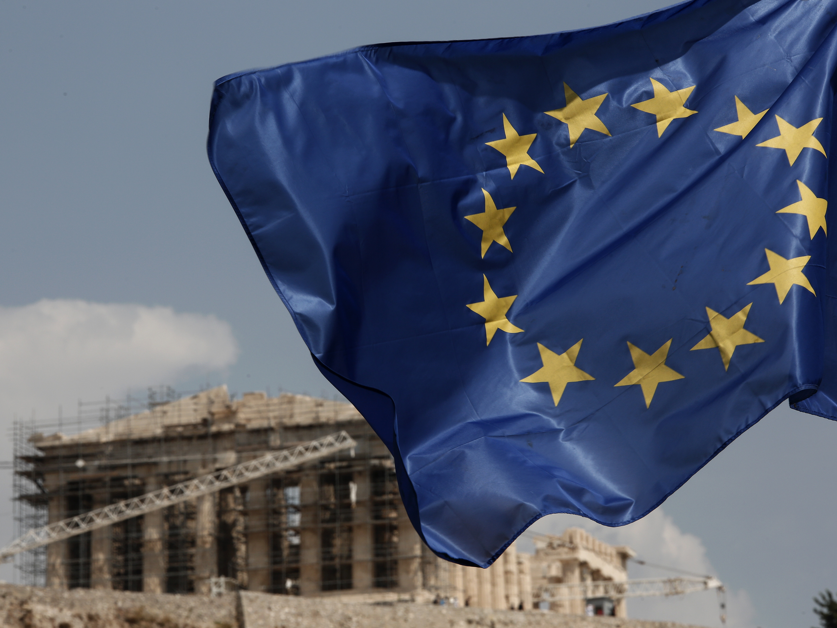 A European Union (EU) flag flutters in front of the temple of the Parthenon in Athens, Greece, on Saturday. Finance ministers on Friday approved the first 26 billion euros ($29 billion) of a vast new bailout package for Greece.