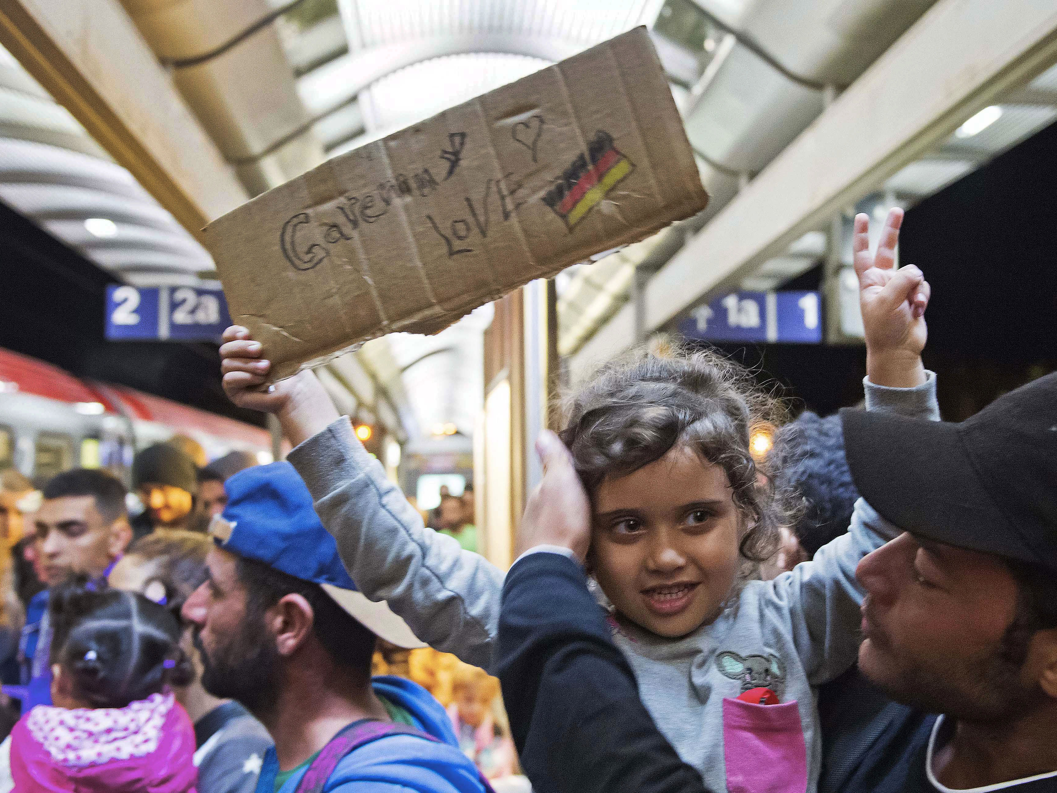 A migrant girl holds a sign expressing her love to Germany as she arrives at the train station in Saalfeld, central Germany, on Saturday. Hundreds of refugees arrived in a train from Munich to be transported by bus to an accomodation center.