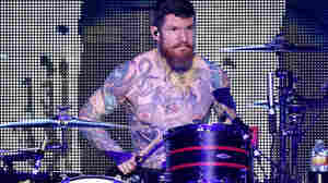 Fall Out Boy drummer Andy Hurley pauses mid-performance to marvel at his own impressive tats.