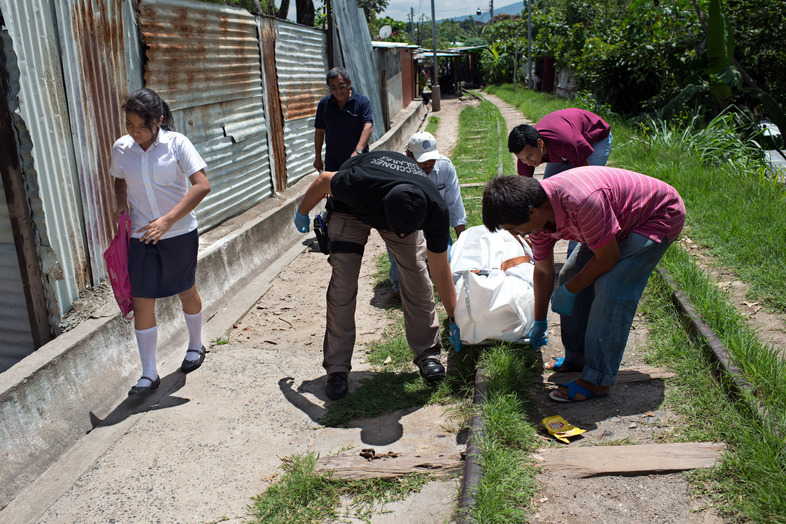 A girl looks away from the body of an assassinated man, who was killed by a gang member in San Salvador. (Encarni Pindado for NPR)