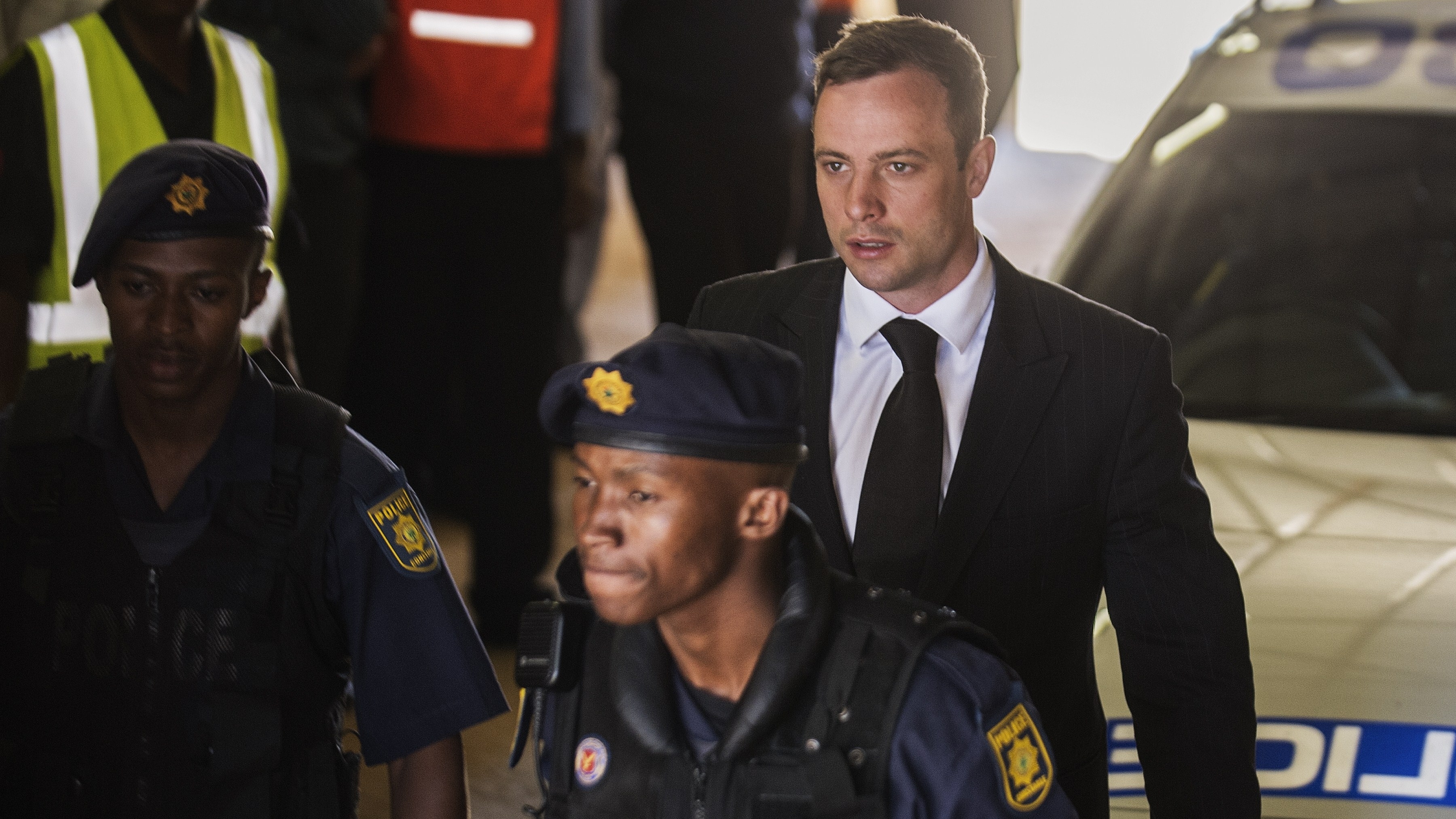 South African athlete Oscar Pistorius (right) is escorted to a police vehicle following his sentencing at the High Court in Pretoria, South Africa, on Oct. 21, 2014.