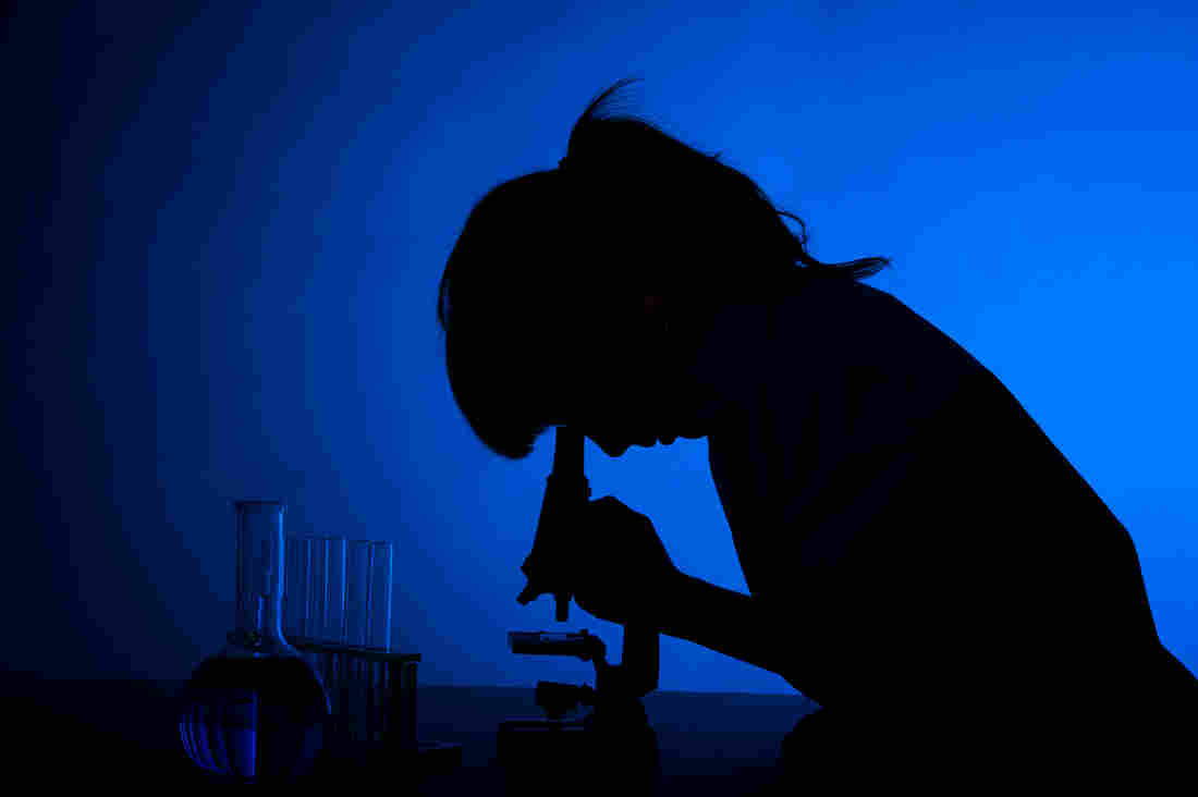Silhouette of a woman scientist at the microscope.