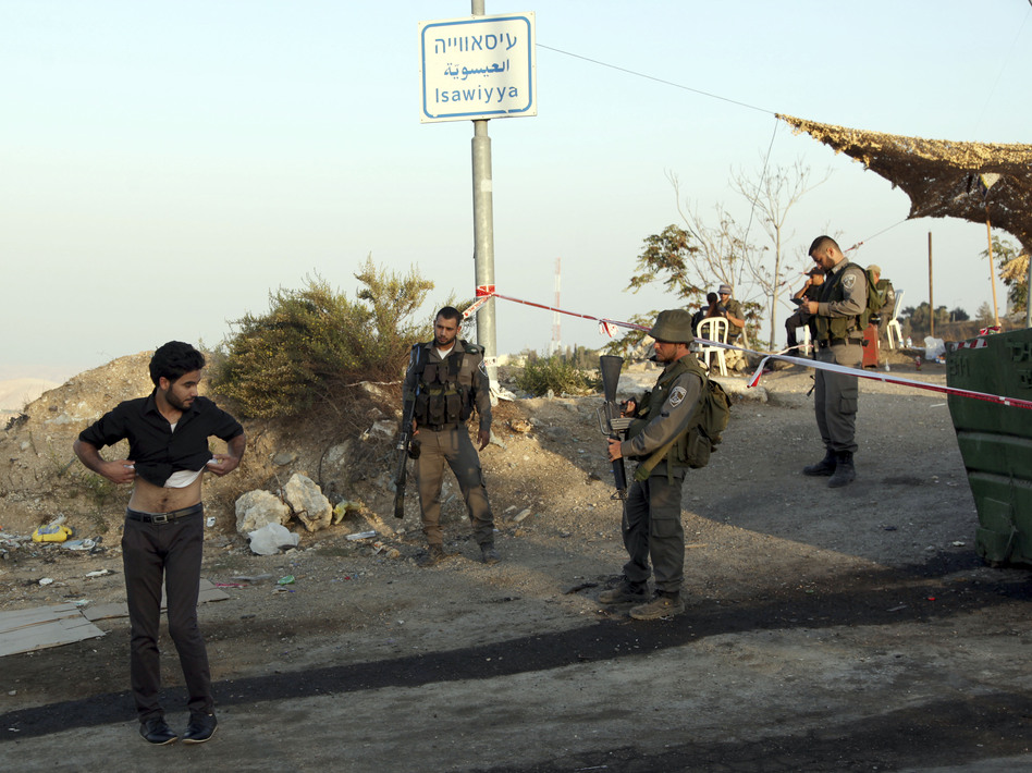 Israeli border police order a Palestinian to lift his shirt at a checkpoint as he exits the Arab neighborhood of Issawiya in Jerusalem. (Mahmoud Illean/AP)