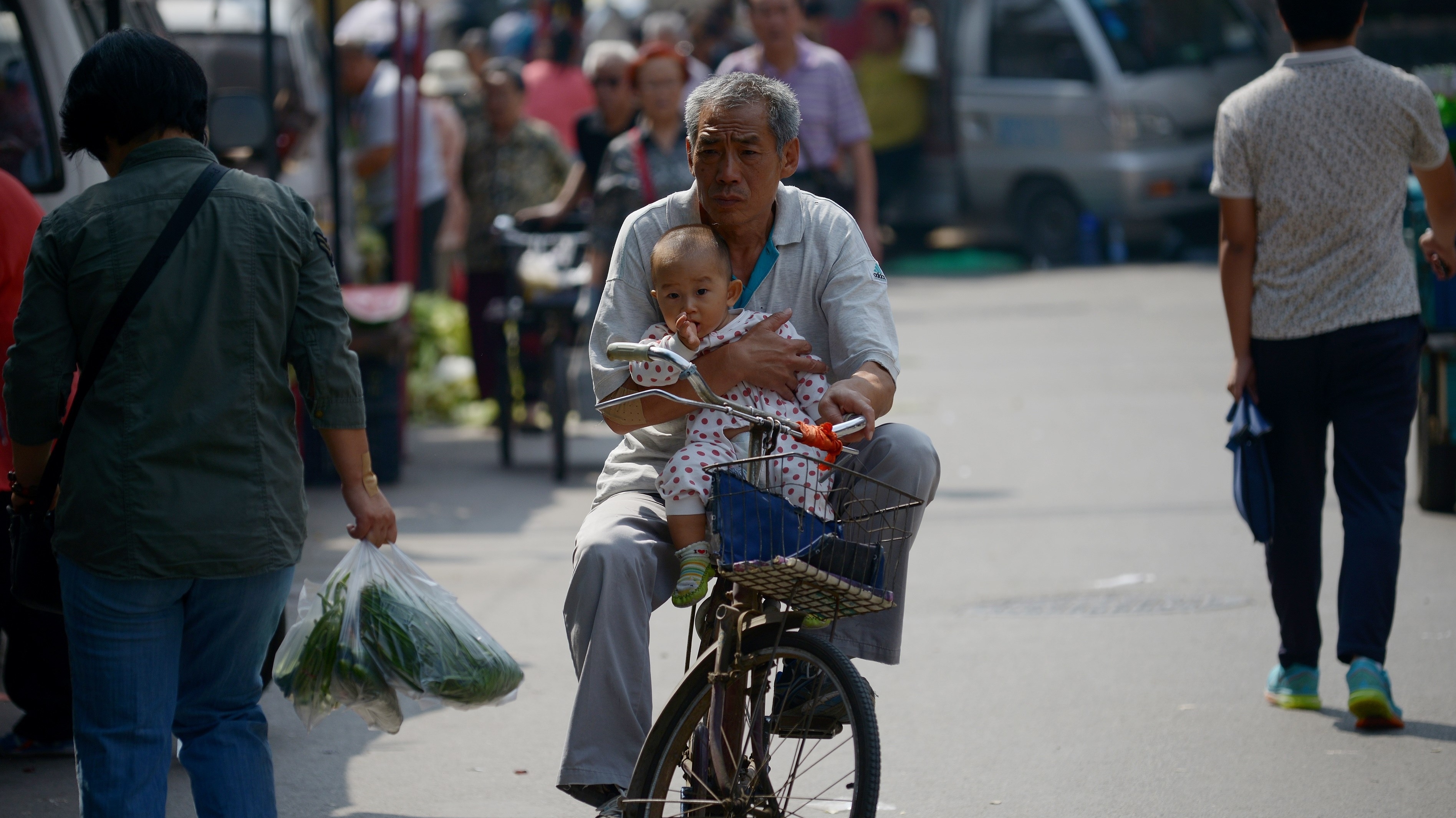 Faced with an aging population, China has eased its one-child policy. Here, an elderly man is seen holding a baby as he rides a bicycle in Beijing last month. (AFP/Getty Images)