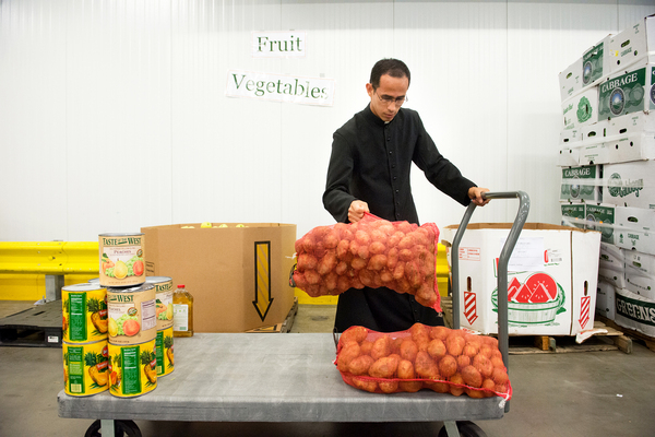 Brother William Valle of the Institute of the Incarnate Word in Chillum, Md., loads potatoes onto his cart at the Capitol Area Food Bank, in Washington, D.C. A new government initiative seeks to engage faith-based groups on food waste — for instance, by using their existing relationships with food banks to redirect excess food to the hungry.