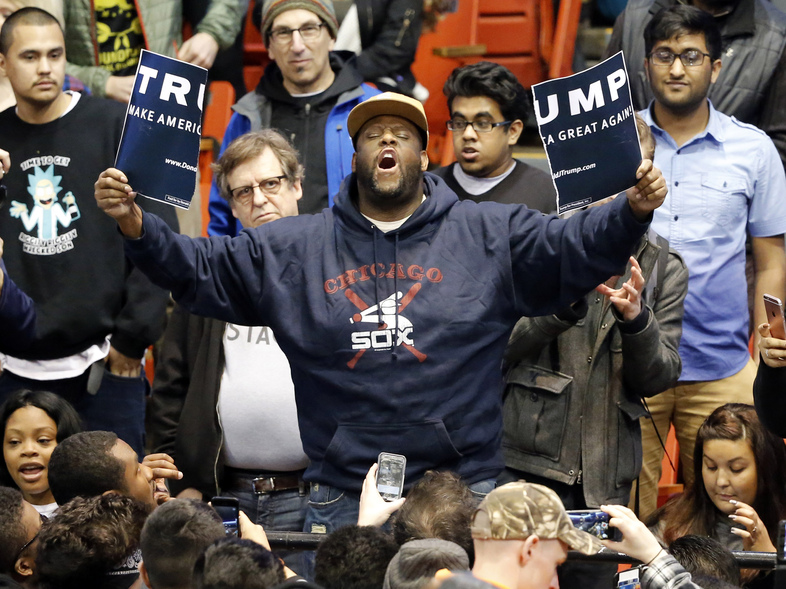 A protester holds up a ripped campaign sign for Republican presidential candidate Donald Trump before a rally on the campus of the University of Illinois-Chicago on Friday. The rally was canceled amid security concerns. (Charles Rex Arbogast/AP)