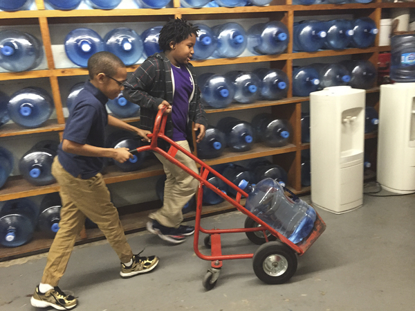 Third-graders Ezekiel White (right) and Emanuel Black push a jug of water to the cafeteria at Southwest Baltimore Charter School.