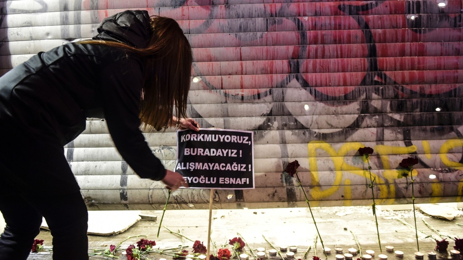 A woman puts a placard at the site of a blast on Istiklal Street, a major shopping and tourist district, in central Istanbul, on Saturday. The sign reads in Turkish, "We are not afraid, we are here, we won't adjust," according to an AFP translation. (Bulent Kilic/AFP/Getty Images)