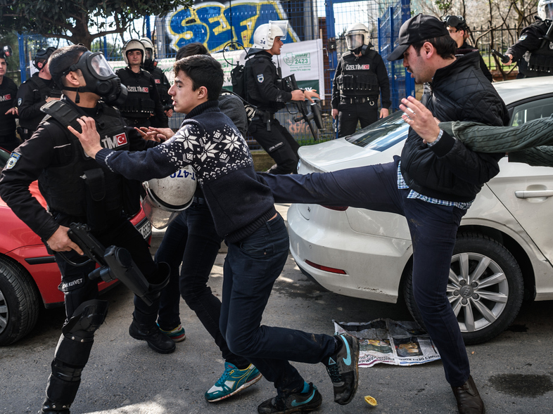 A plainclothes police officer kicks a demonstrator as Turkish anti-riot police disperse supporters in front of the headquarters of the Turkish daily <em>Zaman</em> newspaper in Istanbul on March 5. Turkish authorities seized the headquarters in a midnight raid. (Ozan Kose/AFP/Getty Images)