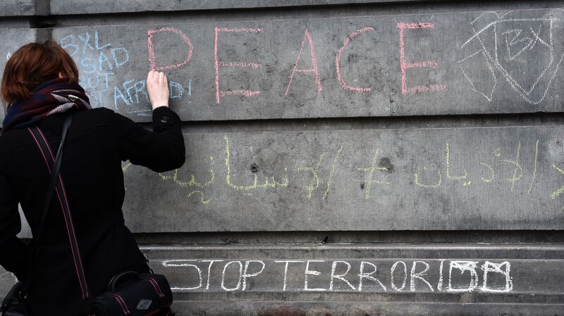 A woman writes a message on a wall in tribute to victims in Brussels on Wednesday, a day after deadly explosions struck the Belgian capital. A woman writes a message on a wall in tribute to victims in Brussels on Wednesday, a day after deadly explosions struck the Belgian capital.