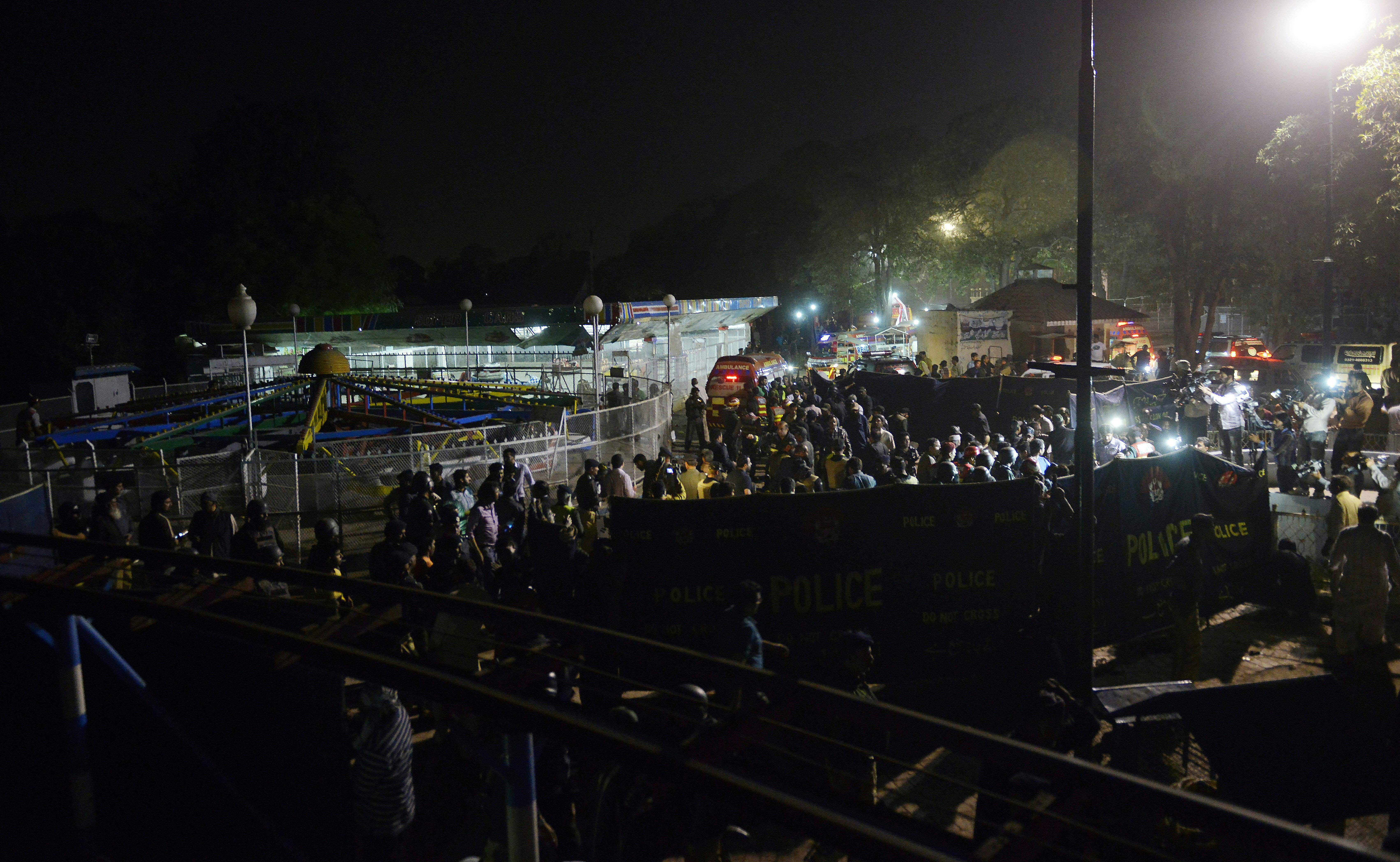 Officials and rescuers gather at the blast site, next to an amusement ride.
