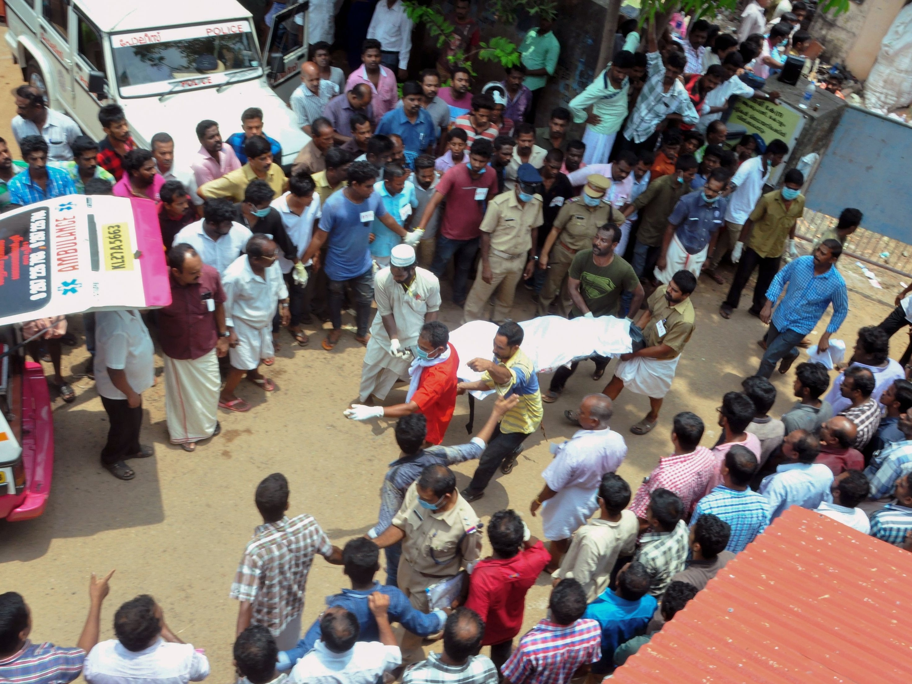 Men carry a body to an ambulance after the fire at a temple in Kerala on Sunday.