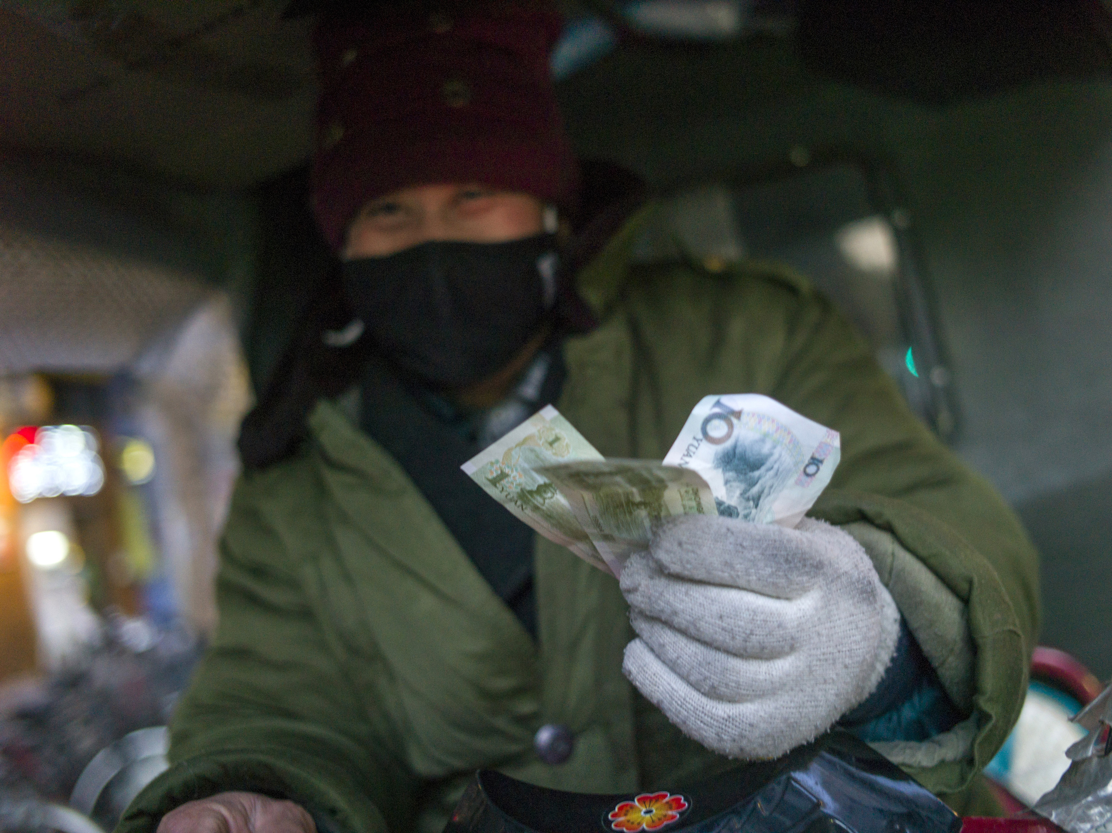 A driver holds up his change from a transaction in Beijing in February. The latest World Economic Outlook offers some good news for China's economy this year.