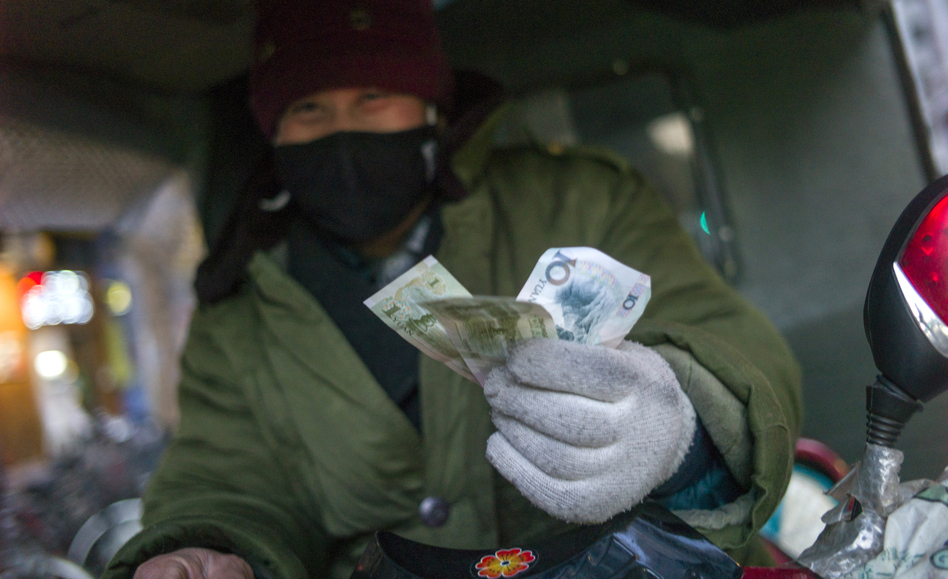 A driver holds up his change from a transaction in Beijing in February. The latest World Economic Outlook offers some good news for China's economy this year. (Fred Dufour/AFP/Getty Images)