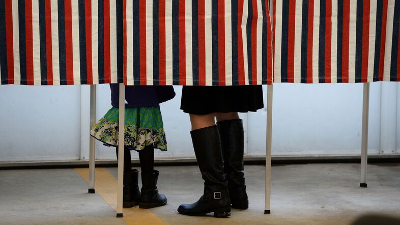 A woman is accompanied by a child inside a voting booth, as she casts her ballot in the New Hampshire presidential primary. (Jewel Samad/AFP/Getty Images)