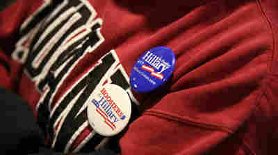 A supporter of Democratic presidential candidate wears campaign buttons as she listens to former President Bill Clinton at an event in Indiana.