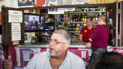 A barman and a customer watch Alejandro Garcia Padilla, governor of Puerto Rico, giving a speech on a television screen in a bar in San Juan, Puerto Rico, on Sunday.