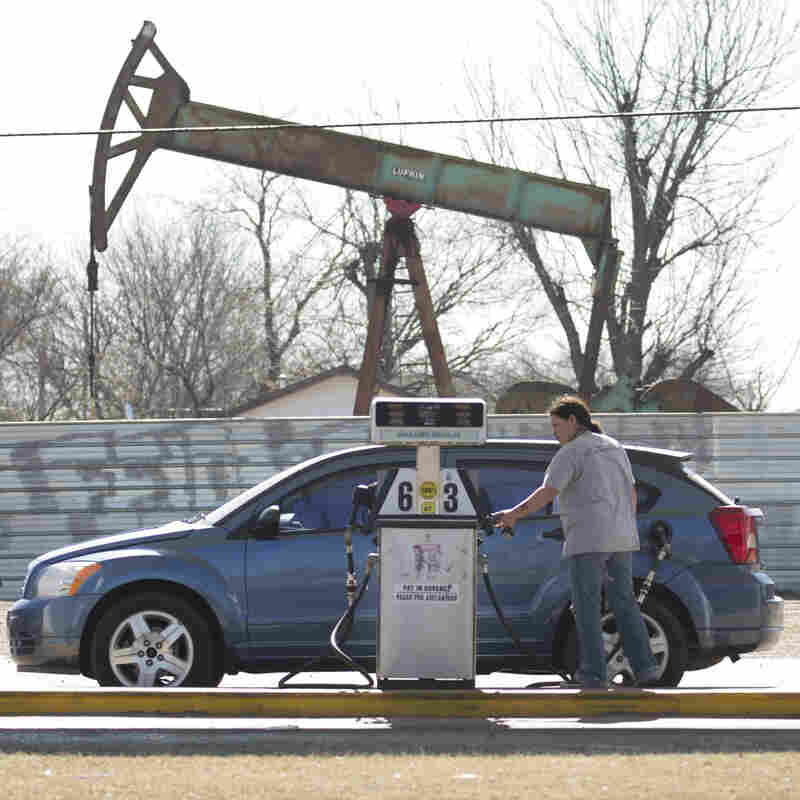 A motorist fills her car at a gas station near an oil field pumping rig in Oklahoma City. A motorist fills her car at a gas station near an oil field pumping rig in Oklahoma City.