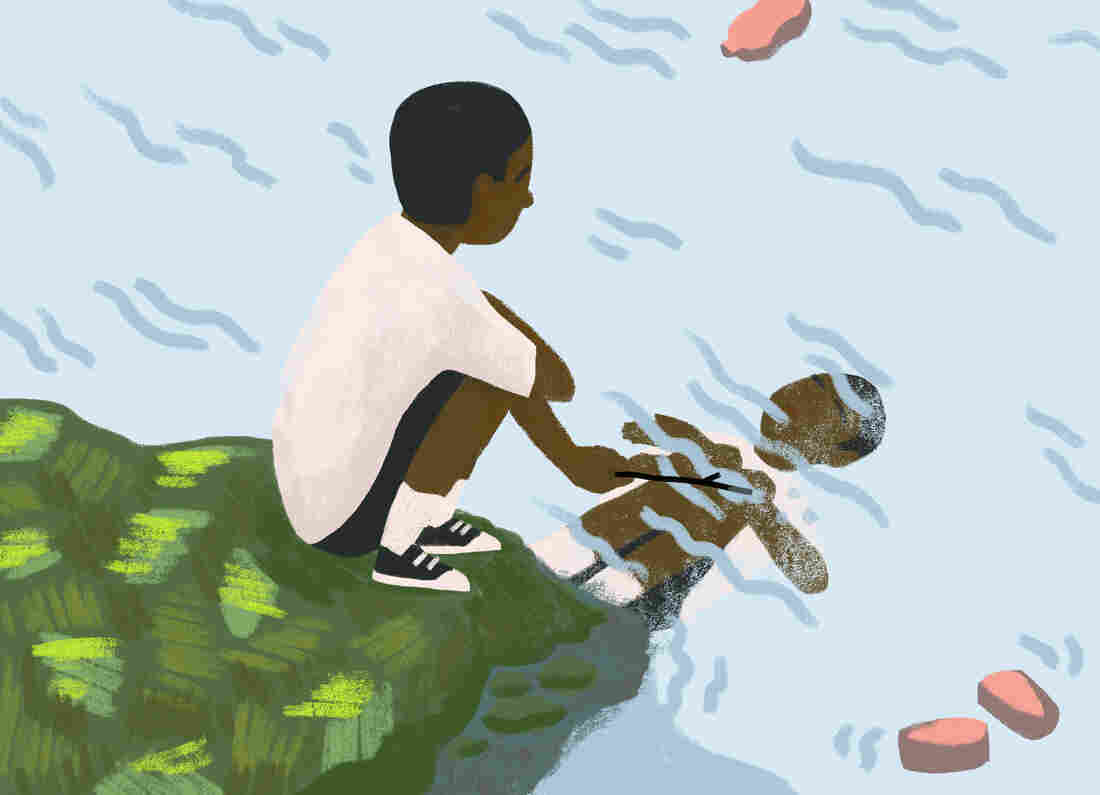 A young boy with stick peers at his reflection in the water.