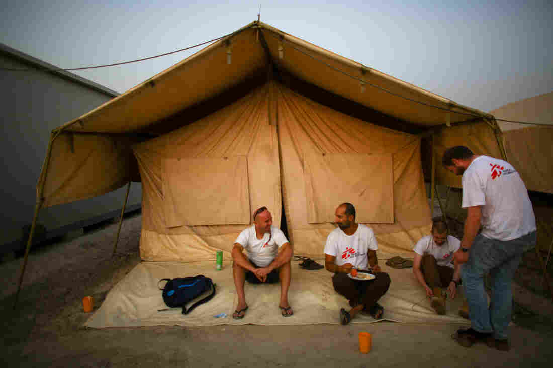 Dr. Nav, finishing up his breakfast, chats with some of his MSF colleagues. The foreign staff live two to a tent. Dr. Nav, finishing up his breakfast, chats with some of his MSF colleagues. The foreign staff live two to a tent.