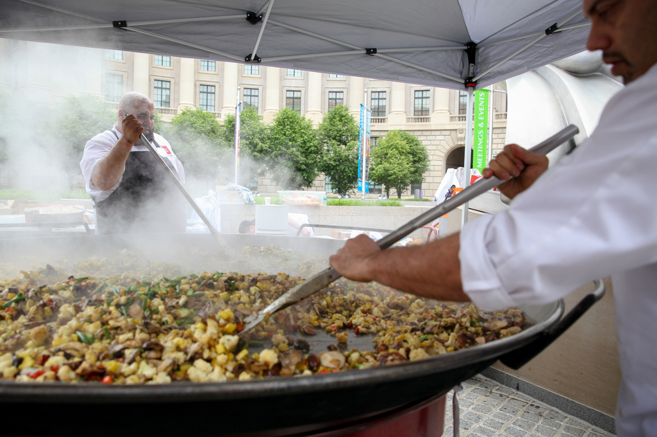 Chefs cook vegetables that will be added to a giant, 7-foot-wide platter of paella. The dish, made from produce diverted from the dump, was served up as part of a free feast for 5,000 in Washington, D.C., Wednesday to raise awareness about food waste. (Morgan McCloy/NPR)