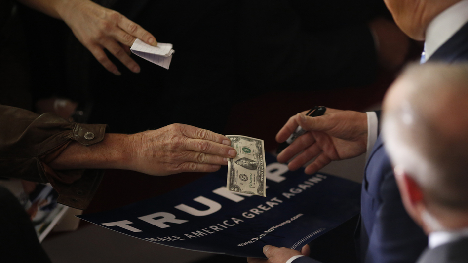 An attendee hands a U.S. $2 bill to Donald Trump during a town hall event in Gaffney, S.C., on Feb. 18. (Luke Sharrett/Bloomberg via Getty Images)