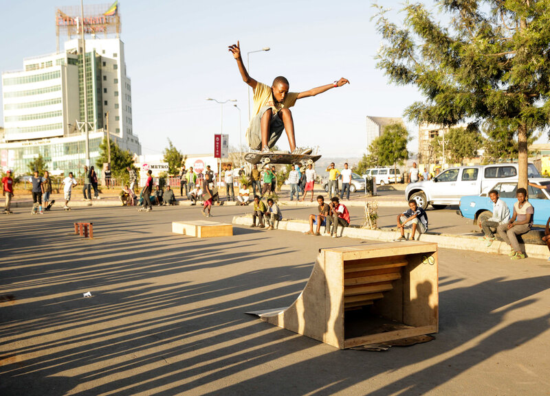 Henok launches off a homemade quarterpipe ramp at a parking lot.