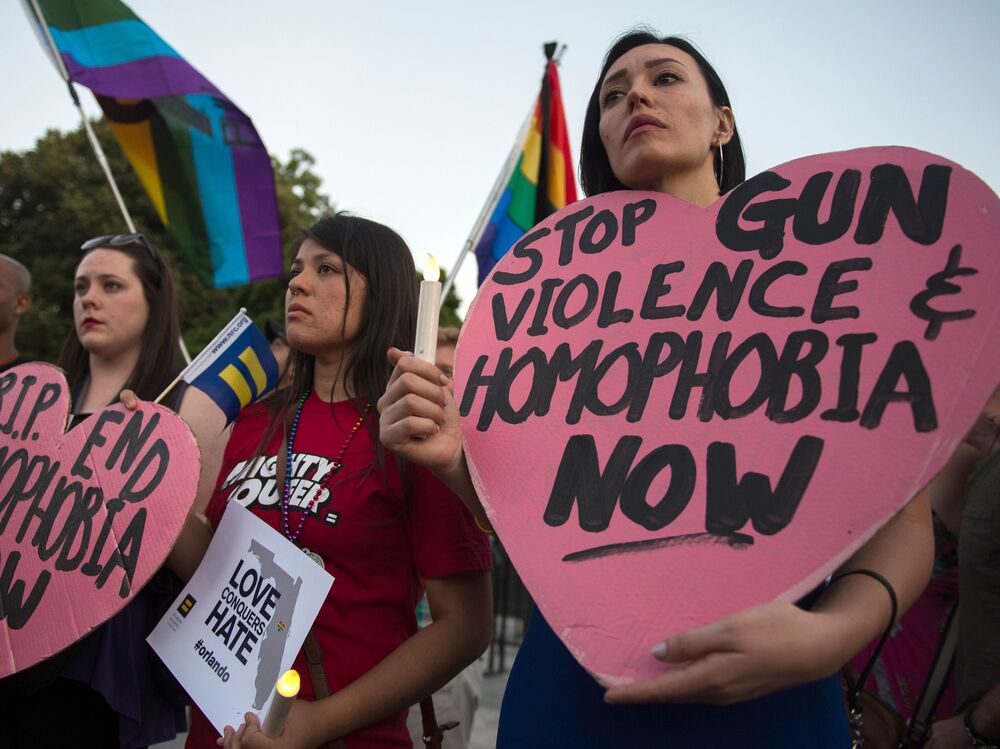 Mourners hold up signs during a vigil in Washington, D.C. in reaction to the mass shooting at a gay nightclub in Orlando, Fla.