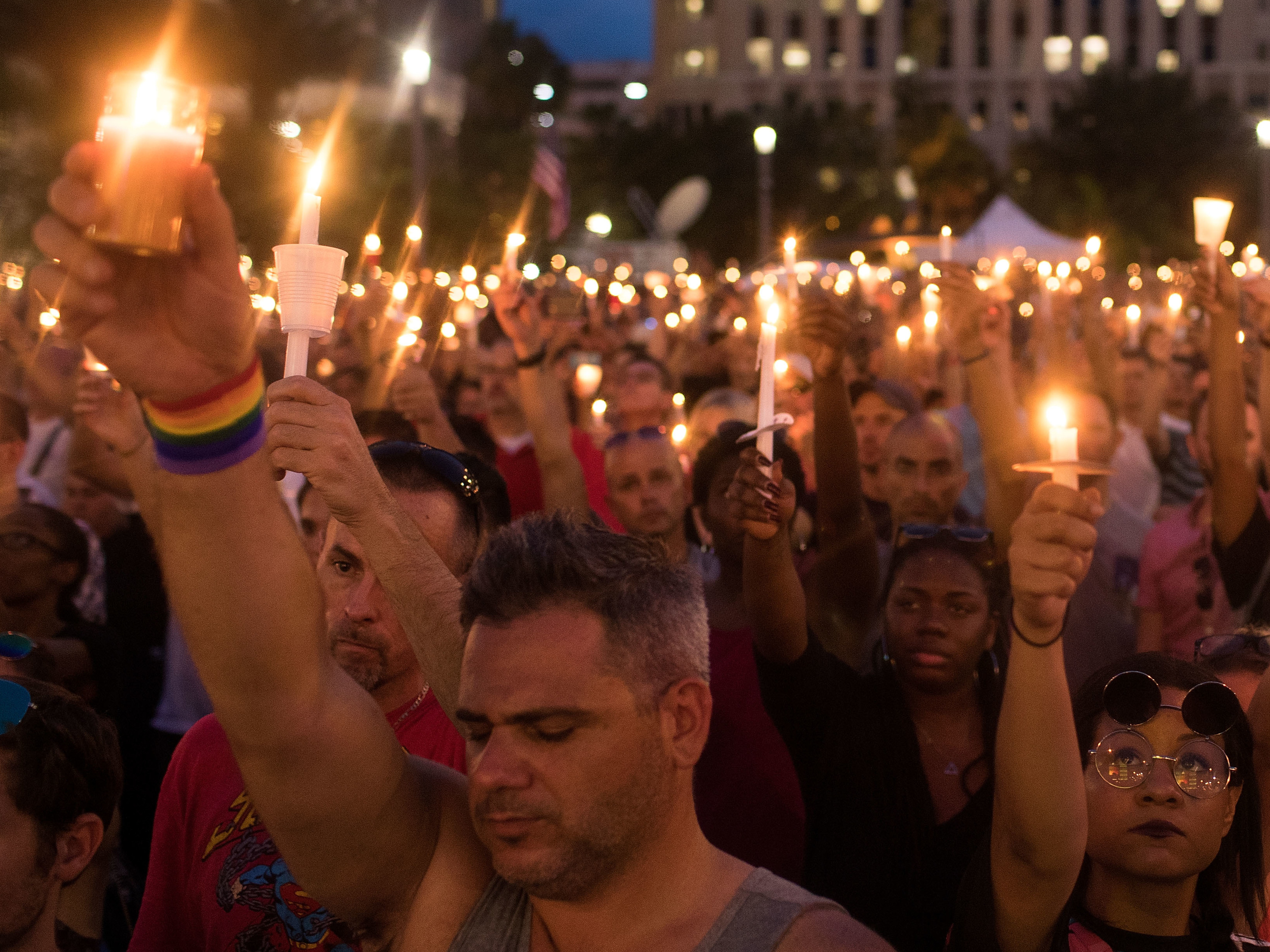 People hold candles during an evening memorial service in Orlando for the victims of the Pulse Nightclub shootings.