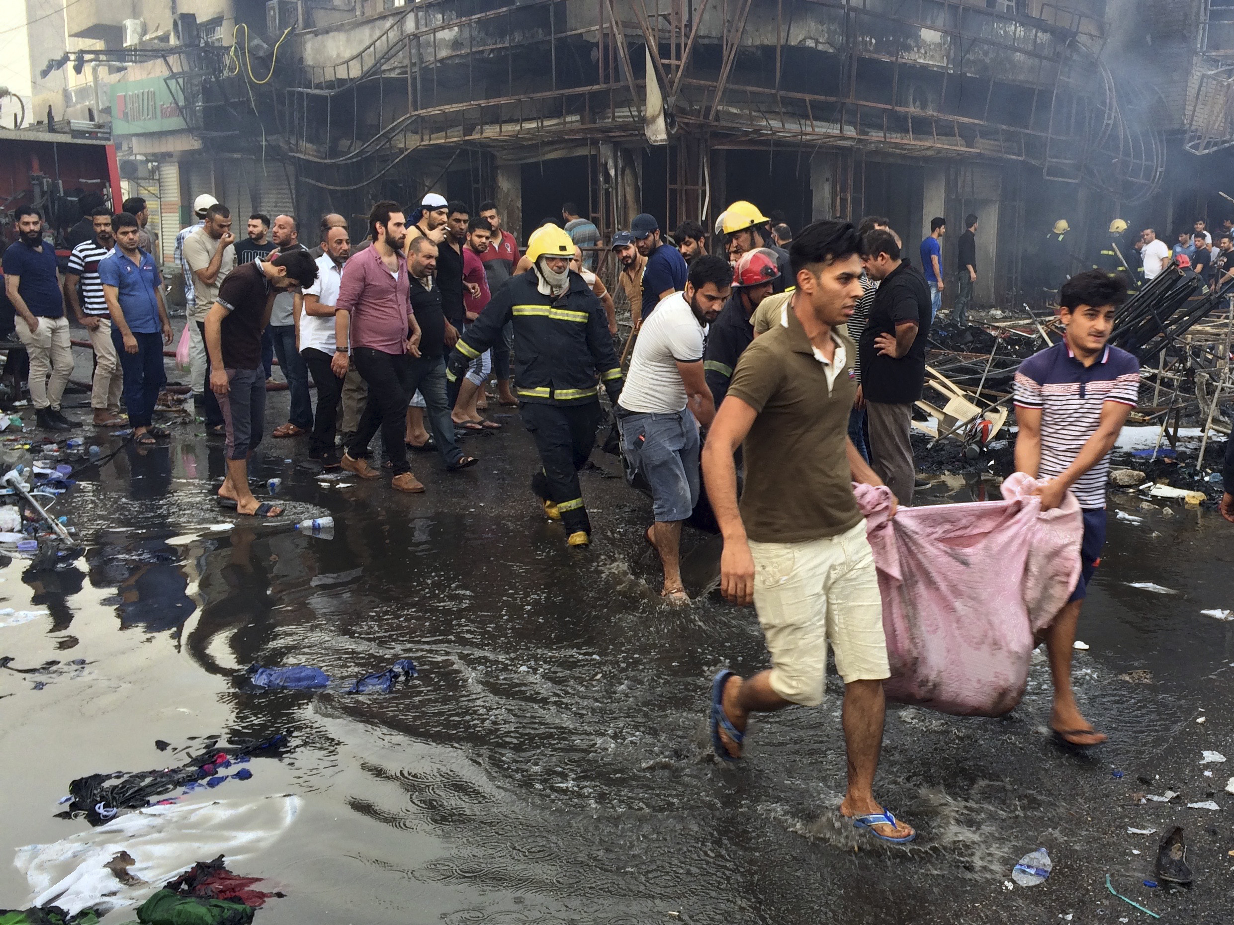 Iraqi firefighters and civilians evacuate bodies of victims killed from a bomb at a commercial area on Sunday in Karada neighborhood, Baghdad, Iraq.