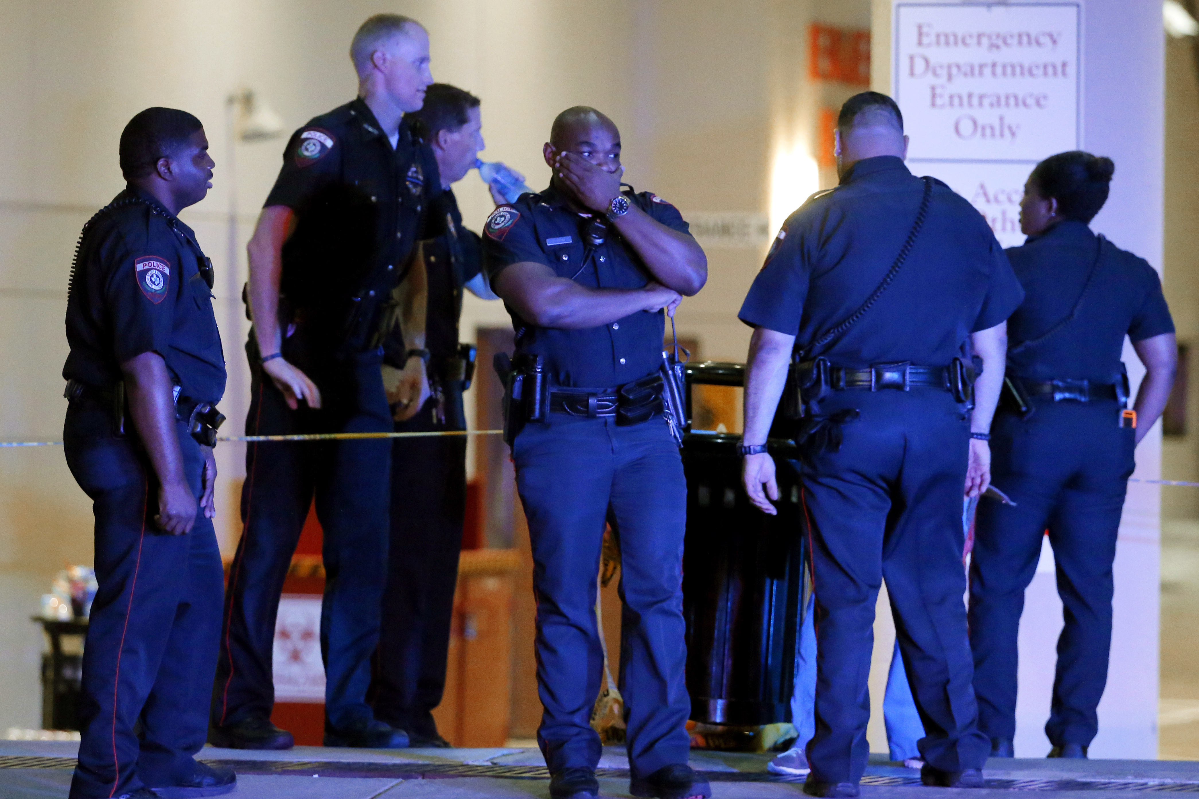 A Dallas police officer covers his face as he stands with others outside the emergency room at Baylor University Medical Center in Dallas. Snipers opened fire on police officers Thursday night, killing some of the officers.