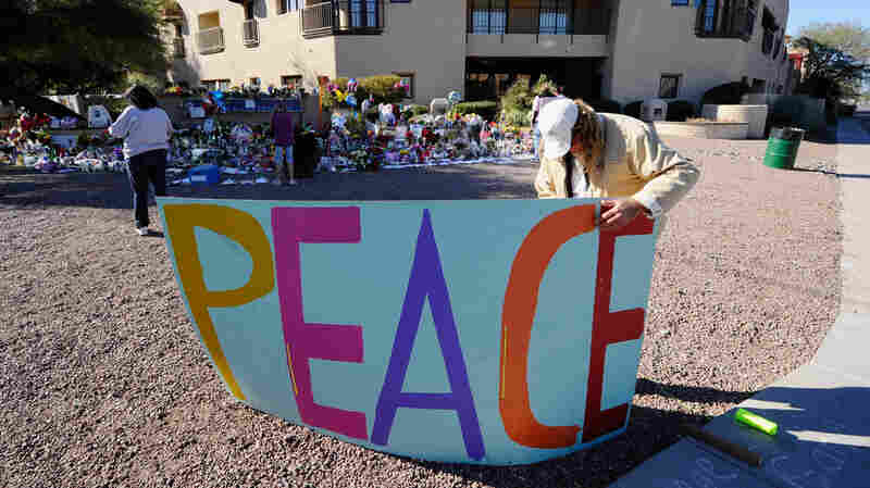 Troy Wine places a large peace sign at a makeshift memorial outside the office of Rep. Gabrielle Giffords in Tucson, Ariz.