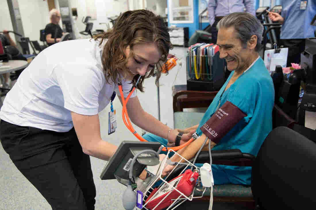 Exercise physiologist Courtney Conners checks Mario Oikonomides' vital signs before his cardiac rehab workout at the University of Virginia Health System clinic.