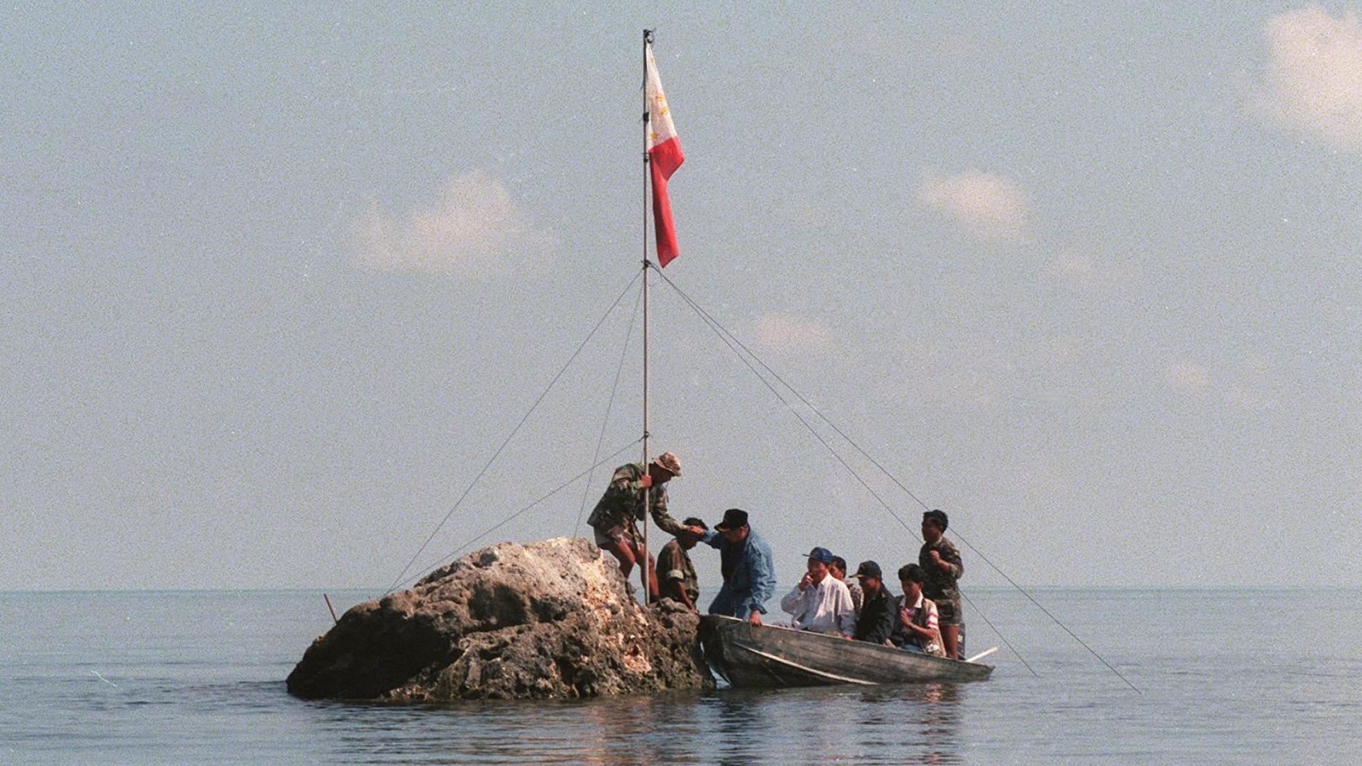 In this file photo, Philippine navy personnel and congressmen land at a rock that is part of Scarborough Shoal bearing the Philippine flag that was earlier planted by Filipino fishermen. (AFP/Getty Images)