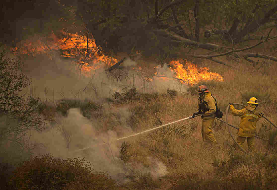 Firefighters battle part of the Sand Fire after flames jumped across a road in Santa Clarita, Calif., on Sunday. As the blaze changed direction multiple times over the weekend firefighters were forced to retreat and thousands of people have been evacuated from their homes.