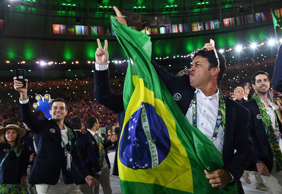 A member of the Brazil delegation waves a flag. The athletes and staff are dancing as a long remix of the classic 1939 song "Aquarela do Brasil" — known to many English-speakers simply as "Brazil" — plays. (AFP/Getty Images)