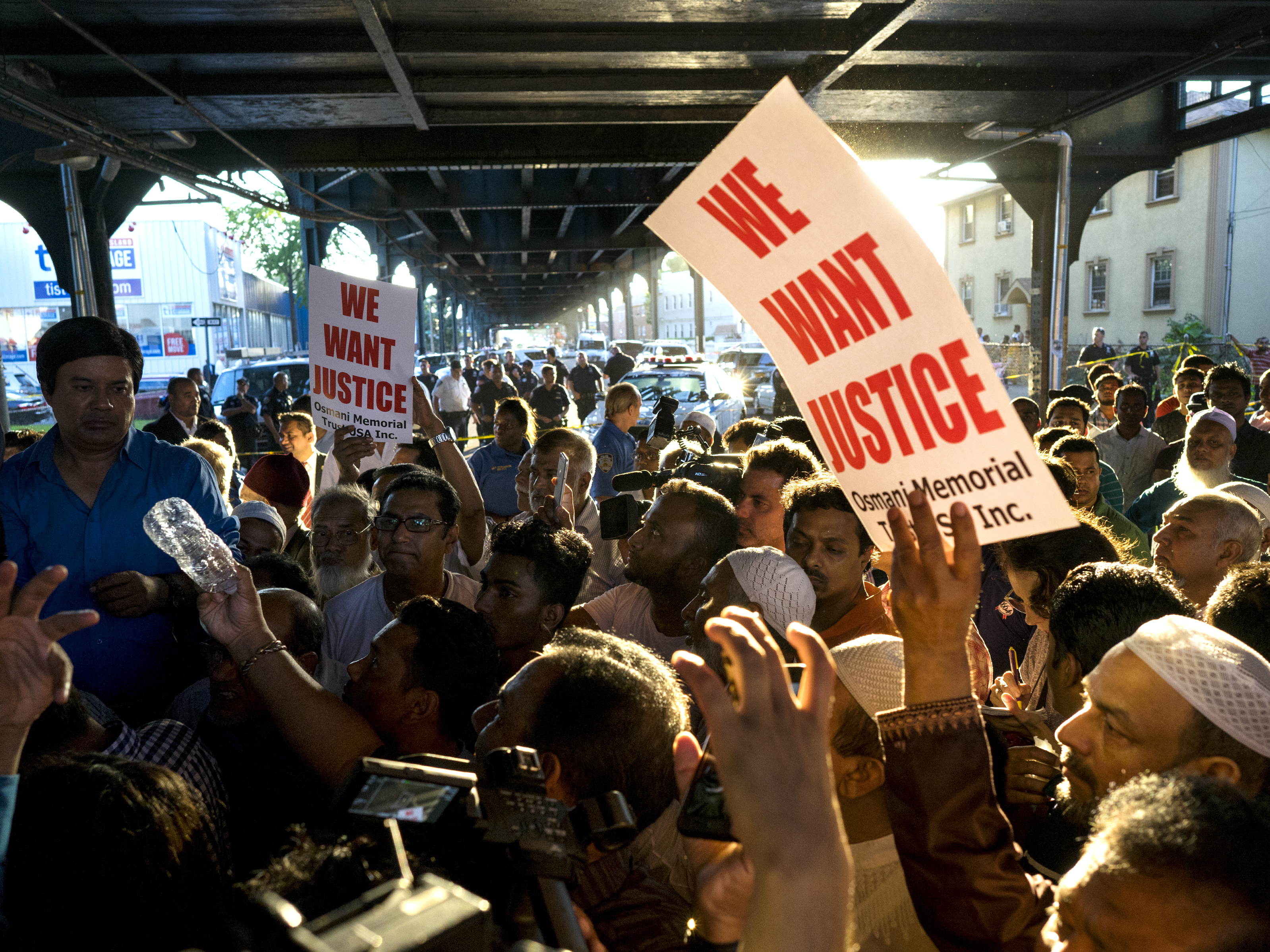 People gather for a demonstration Saturday in the Queens borough of New York, near a crime scene after the leader of a New York City mosque and an associate were fatally shot as they left afternoon prayers.
