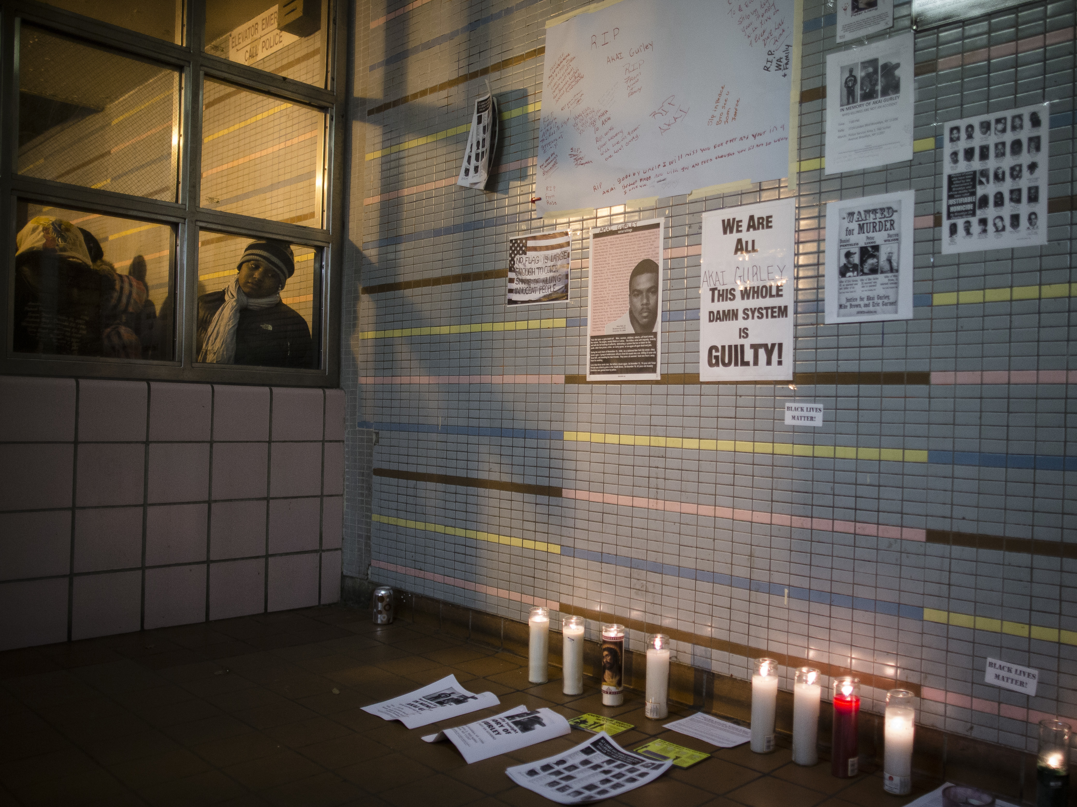 A demonstrator peers at a memorial to Akai Gurley at a public housing complex in Brooklyn, N.Y. Gurley was shot and killed by an NYPD officer in November 2014.