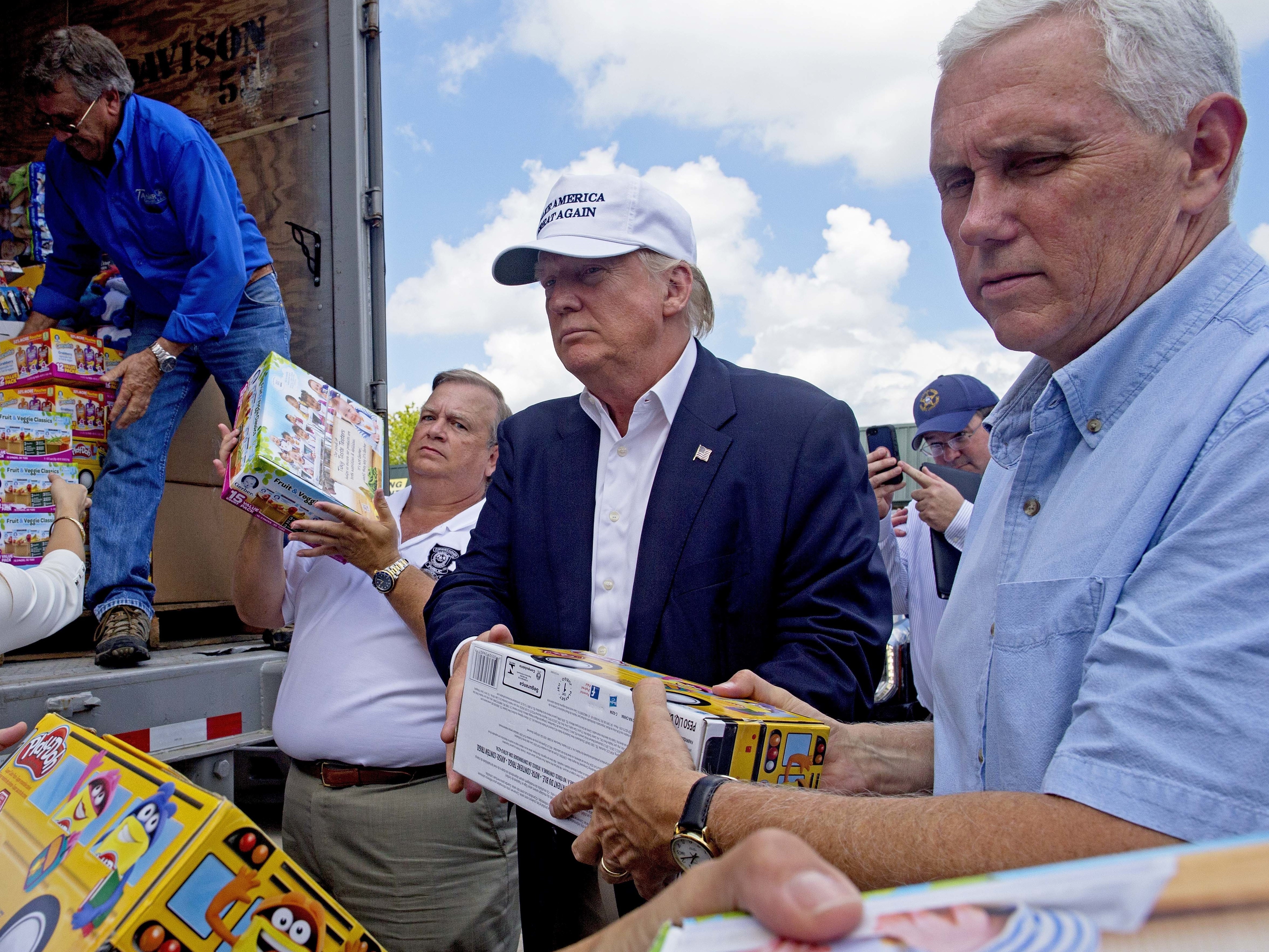 Donald Trump and his running mate, Indiana Gov. Mike Pence, right, help to unload supplies for flood victims during a tour of the flood damaged area in Gonzales, La., Friday.