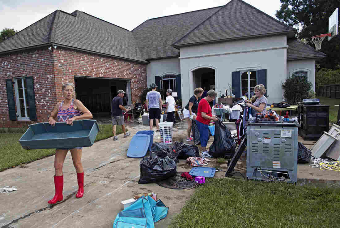 Raven Harelson, 59, (left) carries a drawer to the trash heap in front the home of Sheila Siener, 58, as friends and family help to clean out the flood damaged home in St. Amant, La., on Saturday. Raven Harelson, 59, (left) carries a drawer to the trash heap in front the home of Sheila Siener, 58, as friends and family help to clean out the flood damaged home in St. Amant, La., on Saturday.