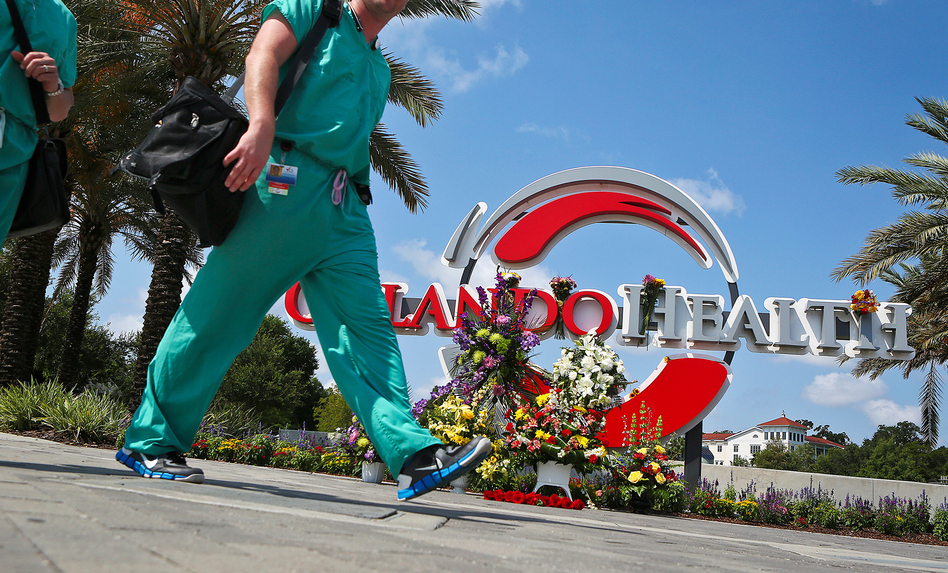 Medical professionals walk by a makeshift memorial set up at the Orlando Health sign in June in Orlando, Fla. (Jacob Langston/Orlando Sentinel/TNS via Getty Images)