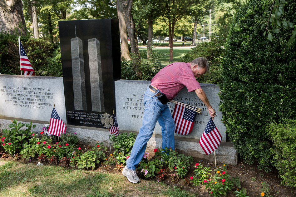 Russell Mercer replaces old U.S. flags with new ones at the Flushing World Trade Center Memorial at Flushing Cemetery in New York City. His stepson, Scott Kopytko, was killed on Sept. 11. (Alex Welsh for NPR)