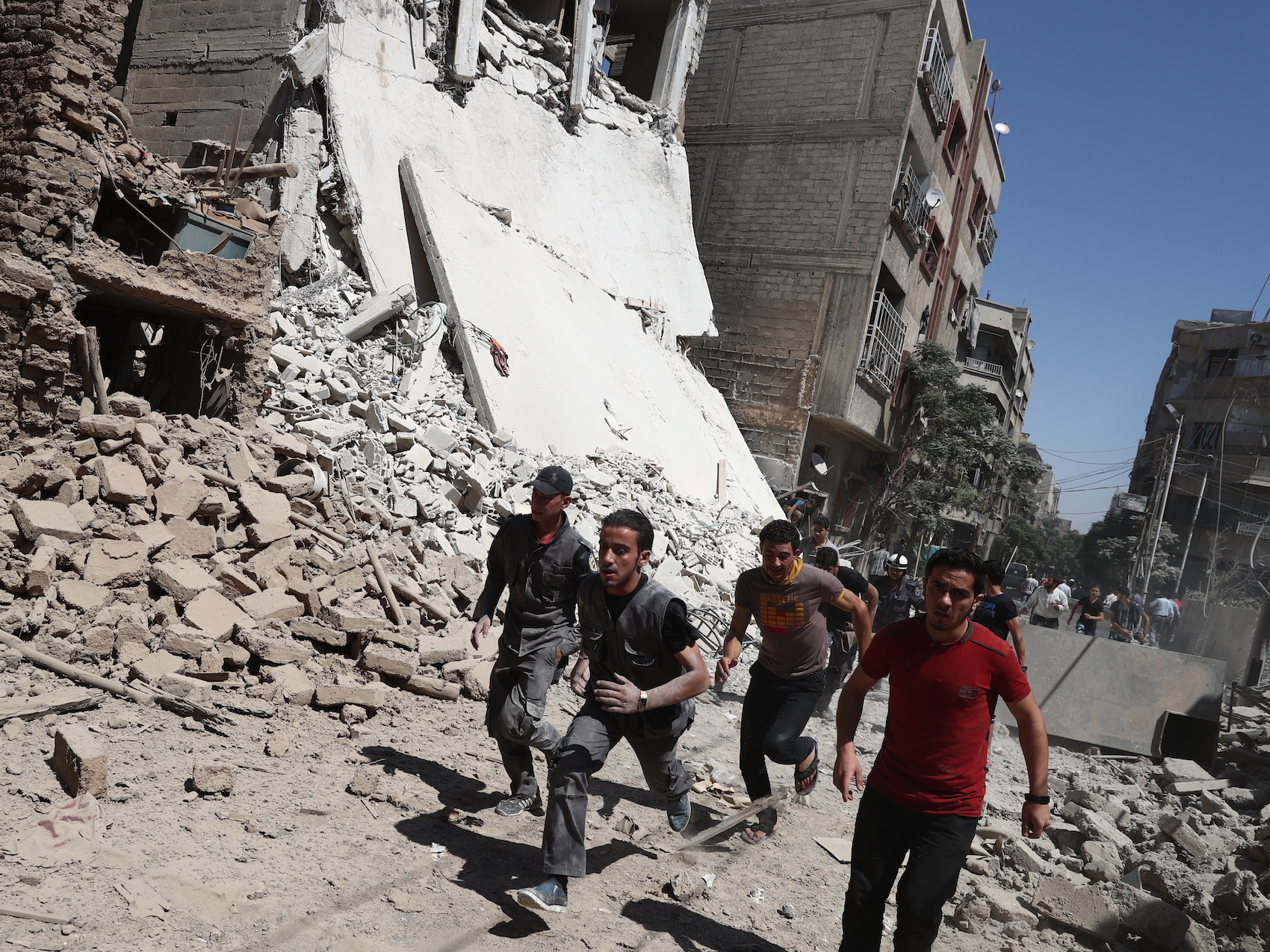 Syrians run for cover during reported government air strikes in the rebel-held town of Douma, east of the capital Damascus, on Sept. 9. Under the plan announced Friday, hostilities are to cease starting at sundown Sept. 12, the start of the Eid al-Adha holiday. (AFP/Getty Images)