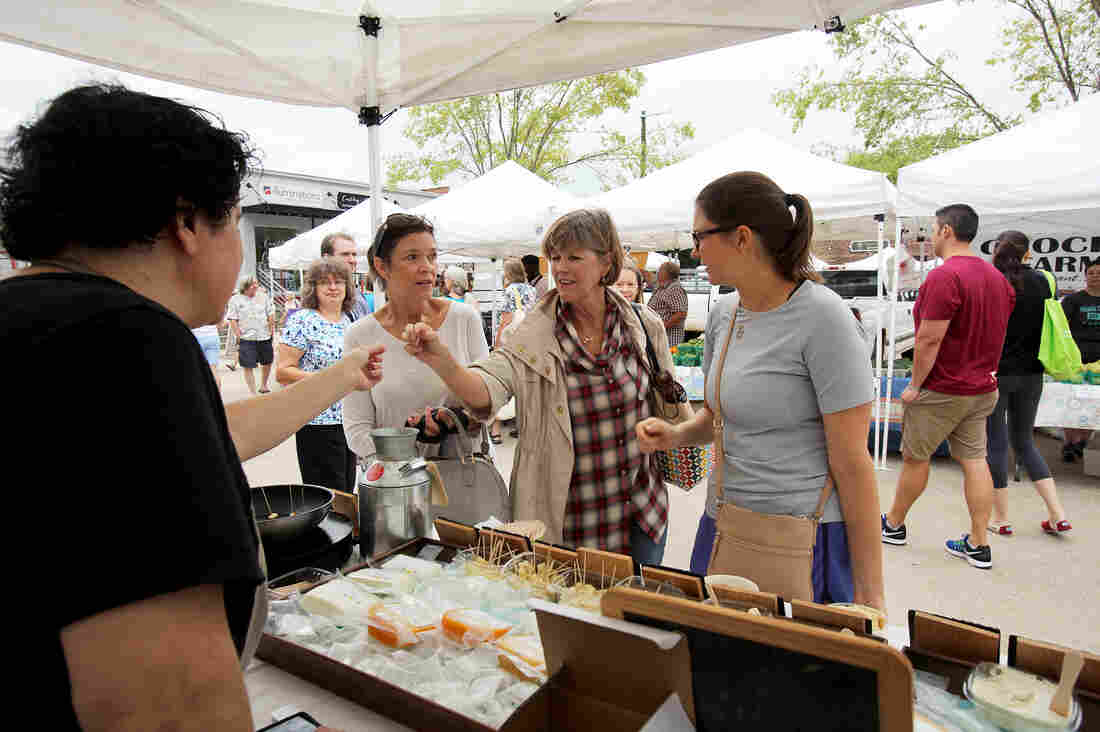 Ana Kelly offers a sample of freshly grilled Halloumi cheese to customers.